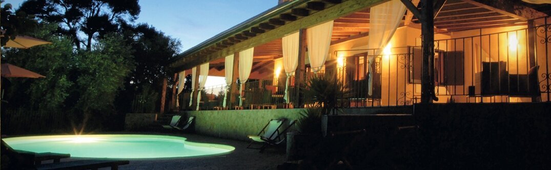 Terrasse éclairée et piscine d’une demeure de charme à la tombée du jour